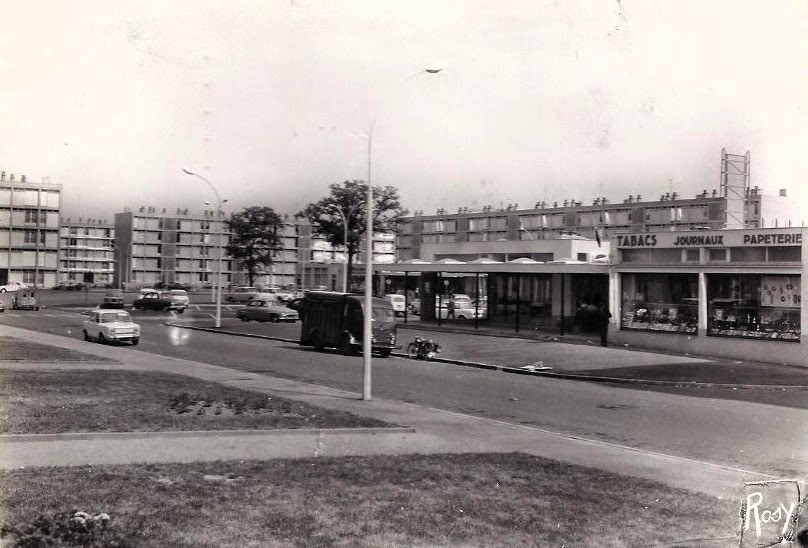 AMRezé_1964-Le-Centre-commercial-du-Chateau-de-Rezet-en-1964-Face-au-Tabac-le-Primeur-et-la-maroquinerie-carte-postale-