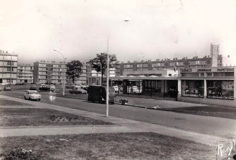 AMRezé_1964-Le-Centre-commercial-du-Chateau-de-Rezet-en-1964-Face-au-Tabac-le-Primeur-et-la-maroquinerie-carte-postale-